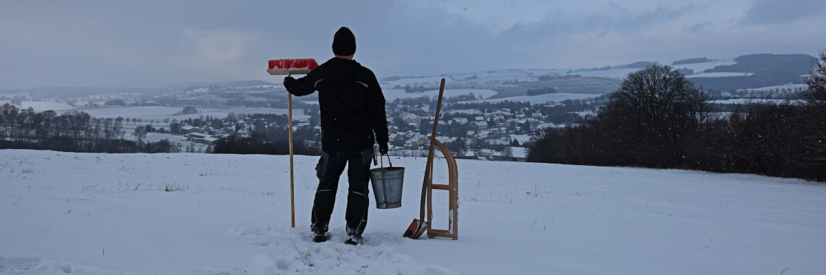 Marek, der Wintermacher – Mann mit Schlitten, Besen und Eimer posiert heroisch vor verschneitem Großwaltersdorf