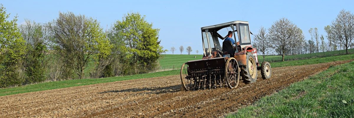 Traktor mit alter Sämaschine bei der Arbeit auf einem Feld im Erzgebirge