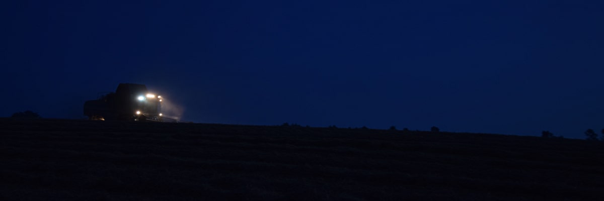 Erntemaschine arbeitet bei Nacht unter hellem Scheinwerferlicht