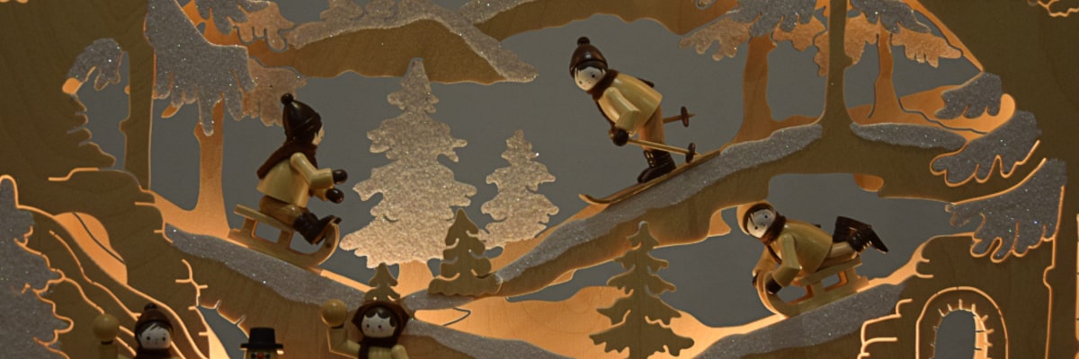 Schwibbogen Winterlandschaft – zwei Figuren rodeln, eine Figur fährt mit Schneeschuhen – Nahaufnahme